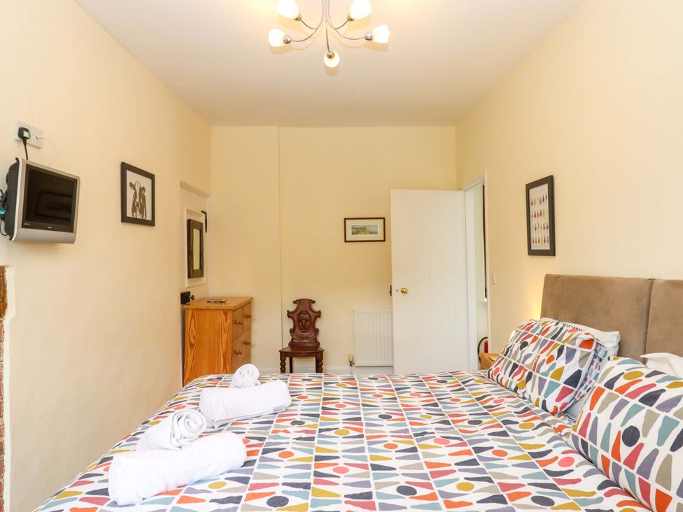 A bedroom with a bed and television at Hornshayne Farmhouse near Honiton