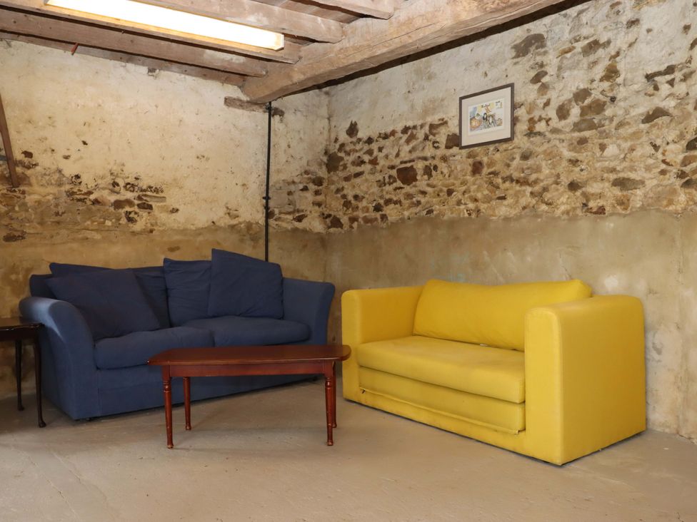 A snug area with blue and yellow sofas and a coffee table at Hornshayne Farmhouse, Farway, near Honiton