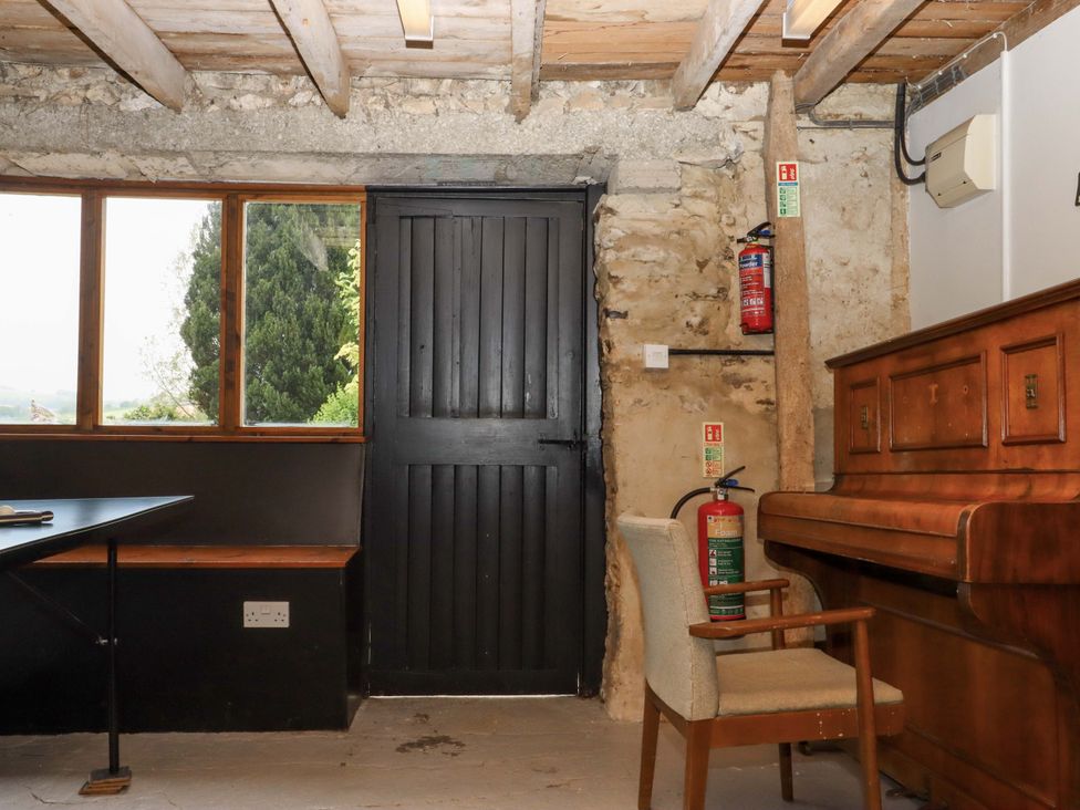 A room with a piano and chair at Hornshayne Farmhouse, Farway, near Honiton