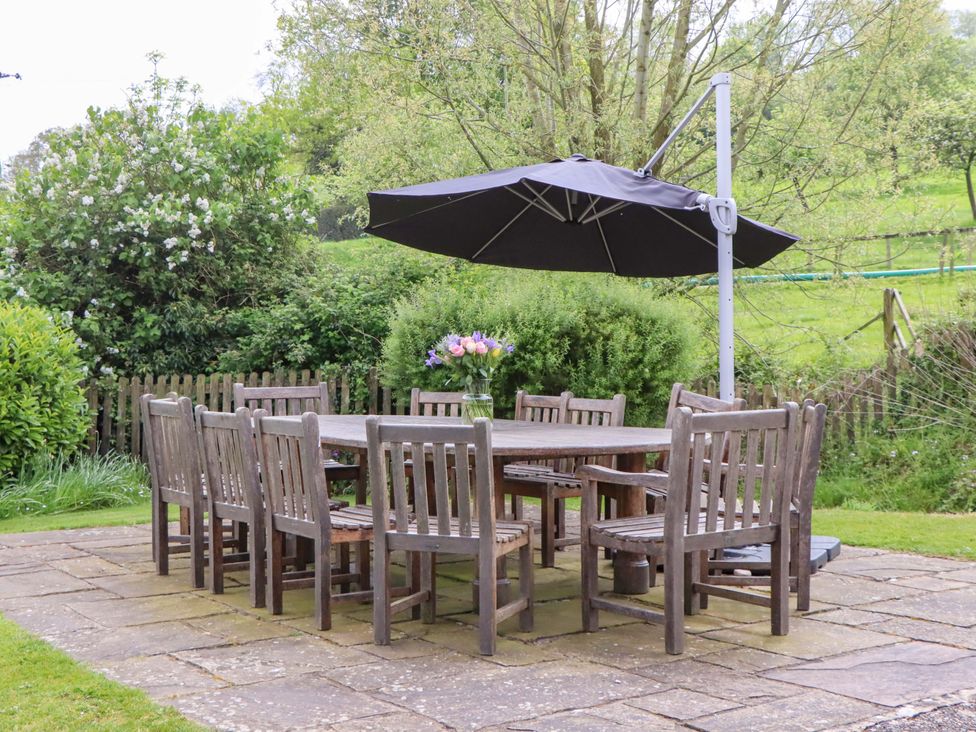 An outdoor dining area with a table and chairs at Hornshayne Farmhouse Farway, near Honiton