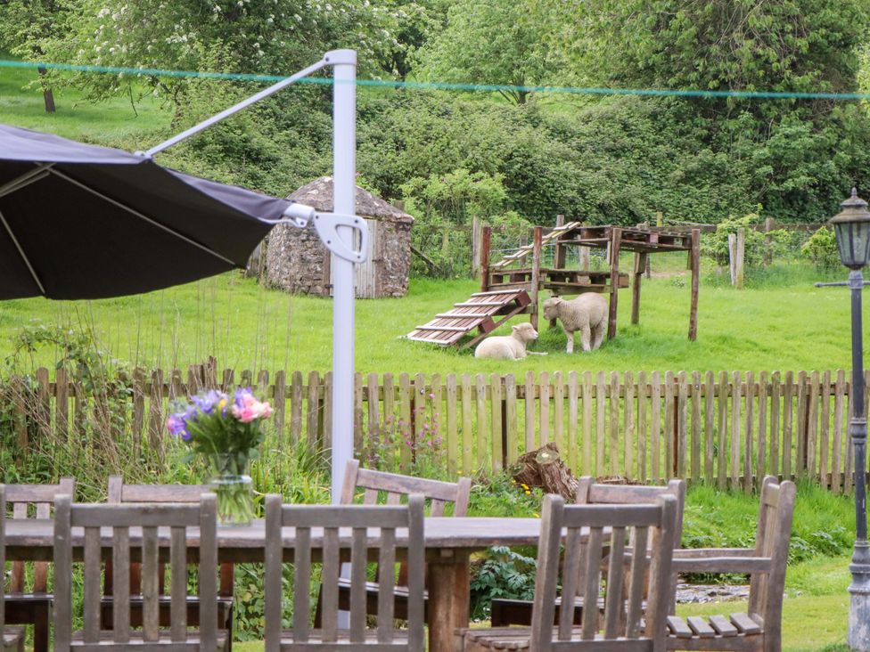 A garden with sheep and a table and chairs at Hornshayne Farmhouse near Honiton