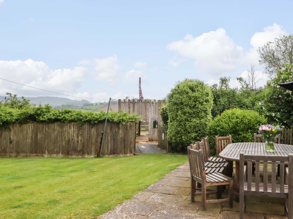 A garden with a wooden table and chairs at Hornshayne Farmhouse in Farway, near Honiton