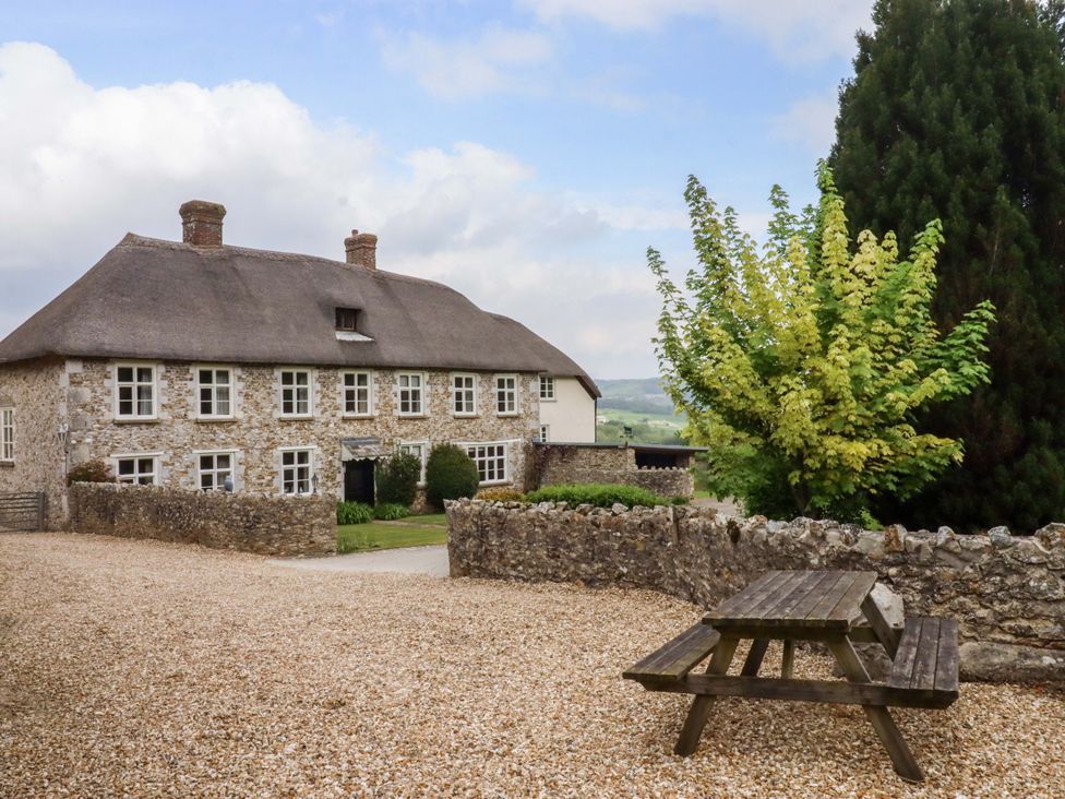 A house with a thatched roof and picnic table at Hornshayne Farmhouse in Farway, near Honiton