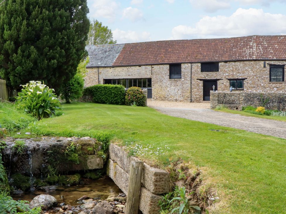 An outdoor area with a building and landscaped grass at Hornshayne Farmhouse, Farway, near Honiton