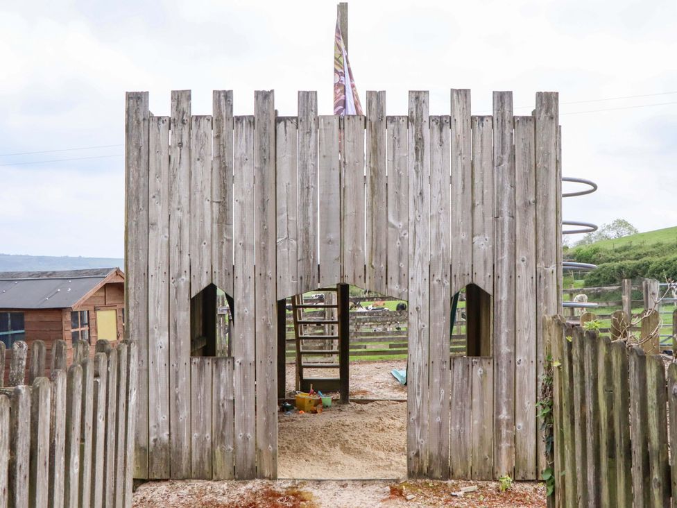 A wooden playhouse with a slide at Hornshayne Farmhouse, Farway, near Honiton