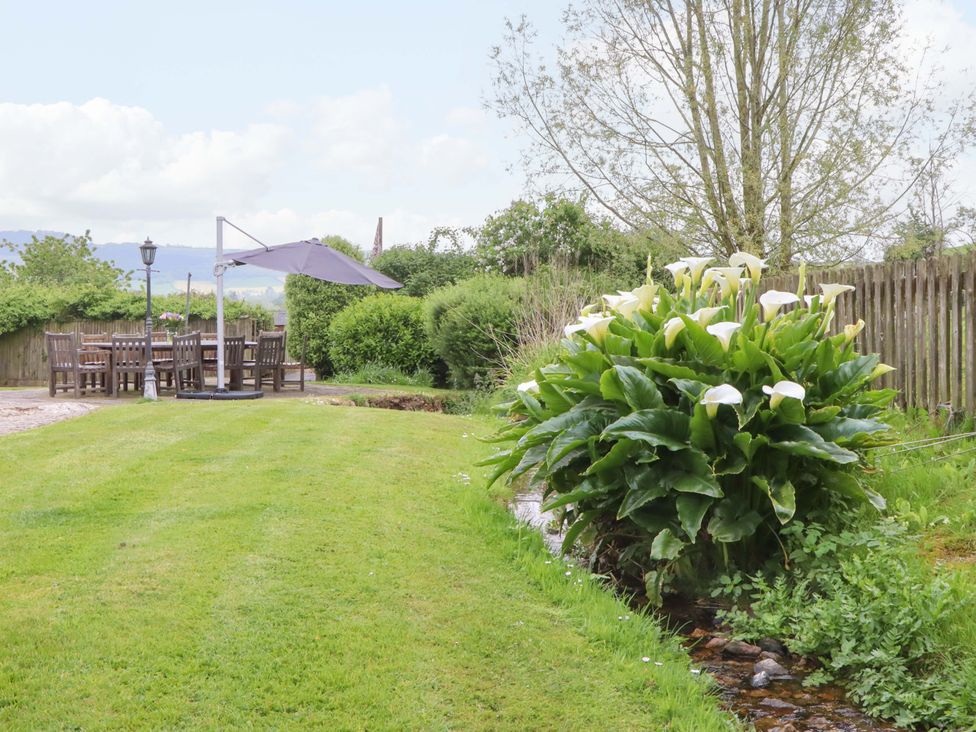A garden with outdoor seating area and flowers at Hornshayne Farmhouse, Farway, near Honiton