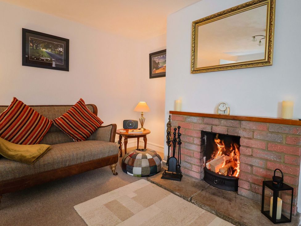 A living room with a fireplace and sofa at Poppy Cottage in Charlton Marshall