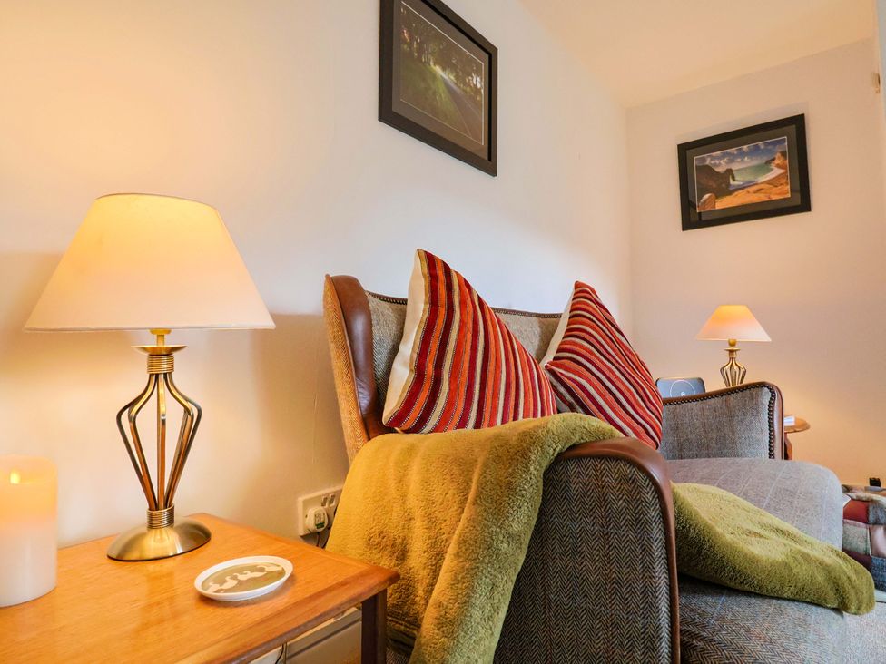 A living room with a sofa and lamps at Poppy Cottage in Charlton Marshall