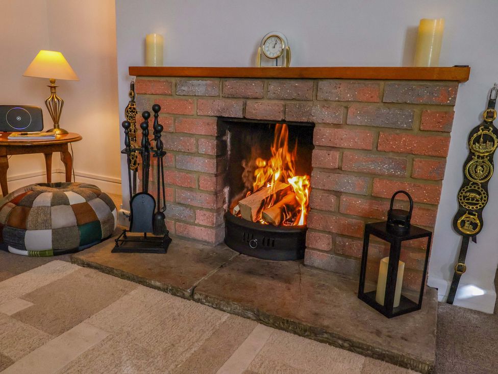A living room with a fireplace and a pouffe at Poppy Cottage in Charlton Marshall