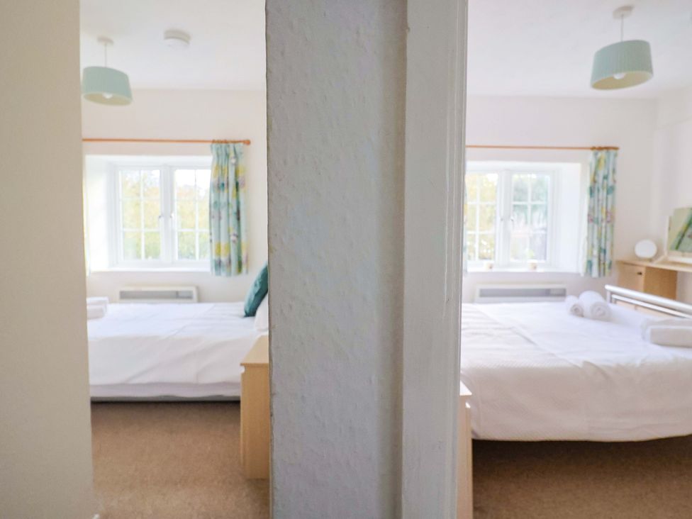 A bedroom with two beds and windows at Poppy Cottage in Charlton Marshall