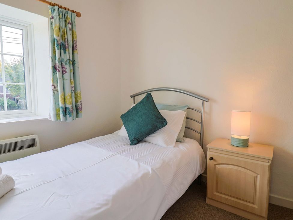 A bedroom with a single bed and nightstand at Poppy Cottage in Charlton Marshall