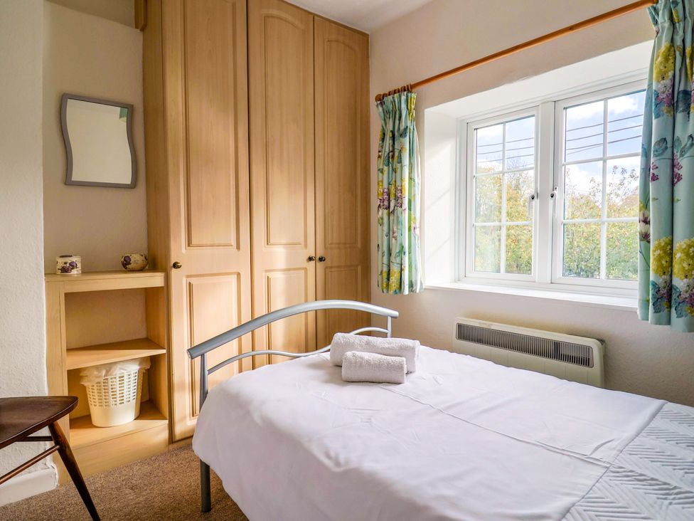 A bedroom with a bed and shelves at Poppy Cottage in Charlton Marshall