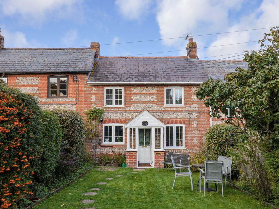 A garden with a house and patio furniture at Poppy Cottage in Charlton Marshall