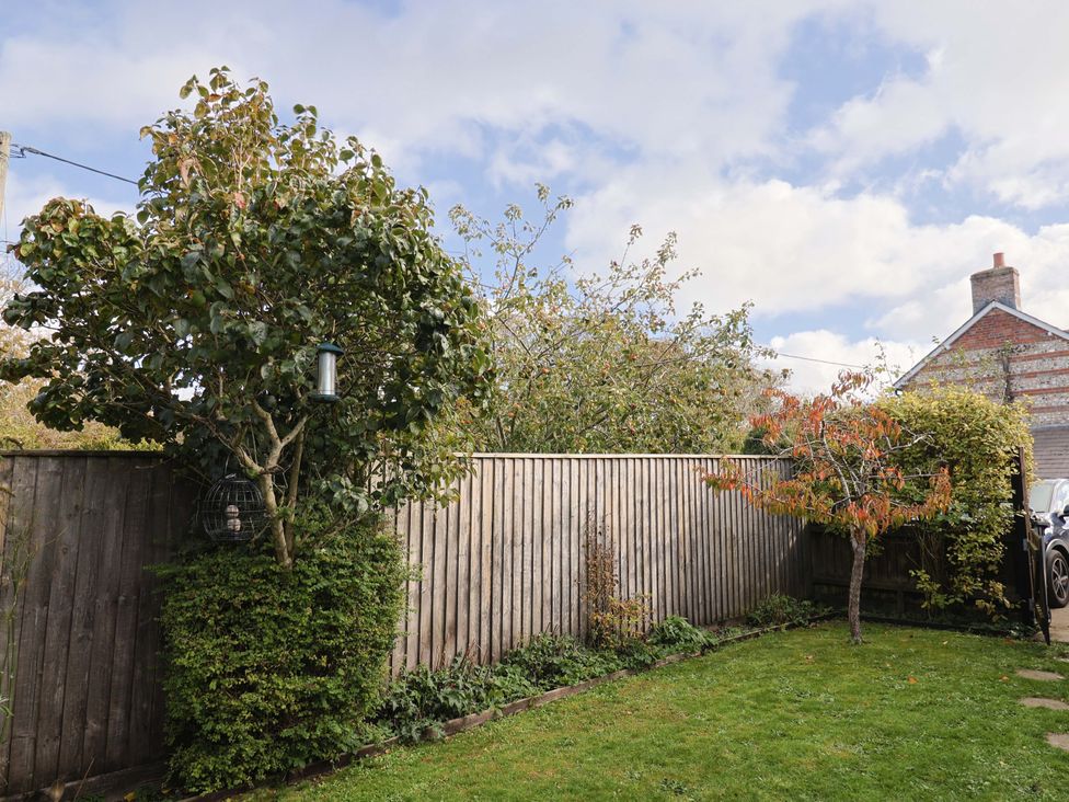 A garden with trees and a fence at Poppy Cottage in Charlton Marshall