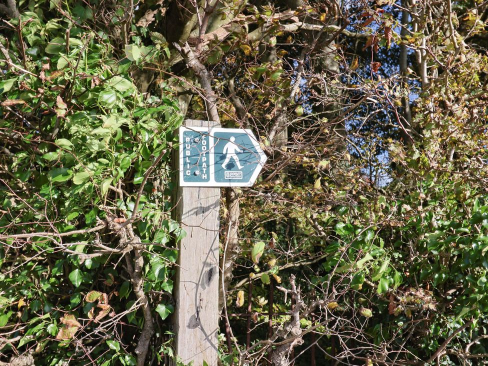 A footpath sign on a wooden post surrounded by bushes at Poppy Cottage Charlton Marshall