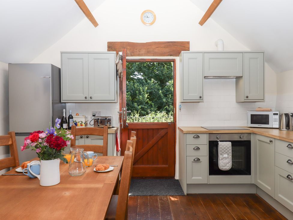 A kitchen with a table and chairs at The Cottage in Sampford Courtenay