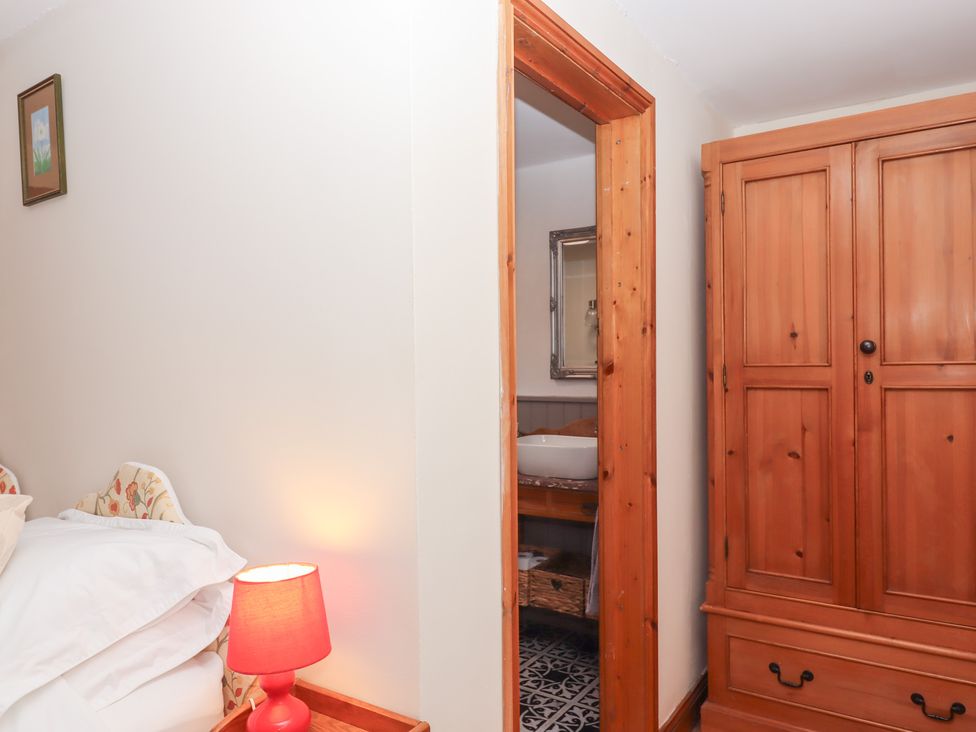 A bedroom with a wardrobe and a bathroom entrance at The Cottage in Sampford Courtenay