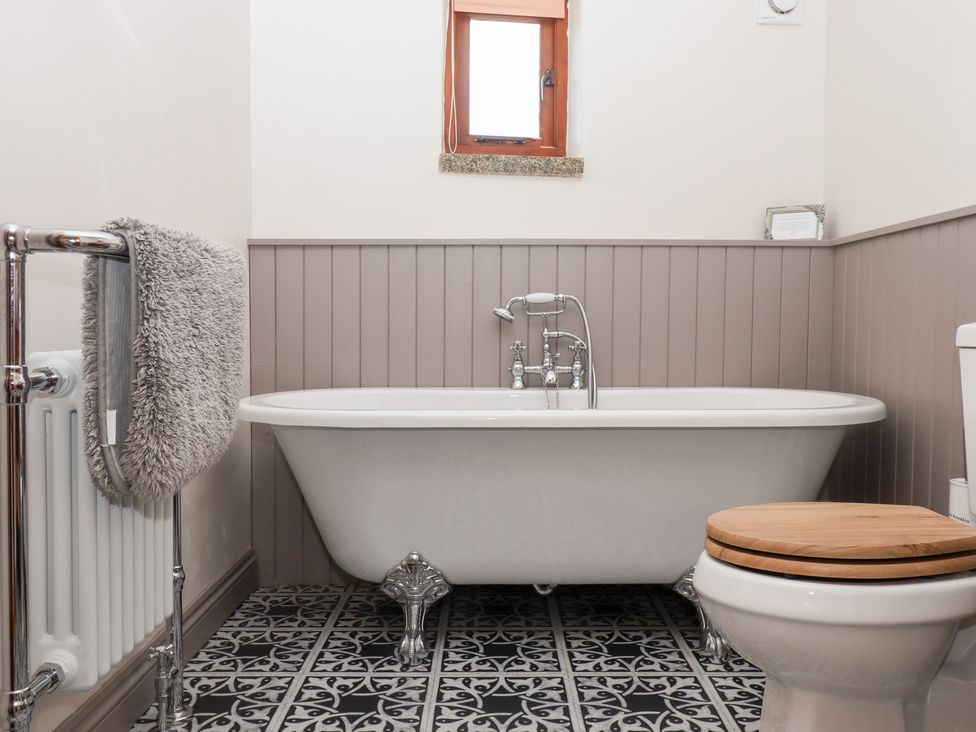 A bathroom with a bathtub and toilet at The Cottage in Sampford Courtenay