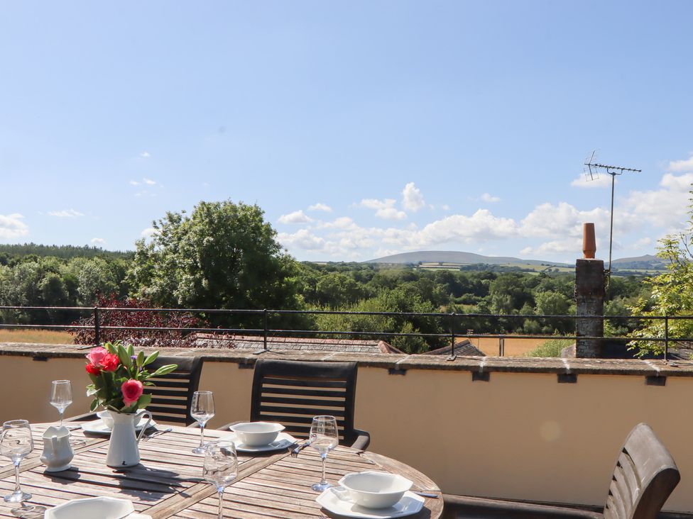 An outdoor dining area with a table and chairs overlooking a landscape at The Cottage in Sampford Courtenay