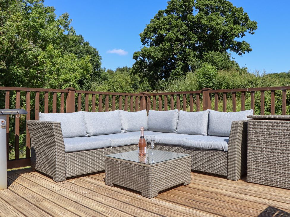 A deck with an outdoor sofa and coffee table at The Cottage in Sampford Courtenay