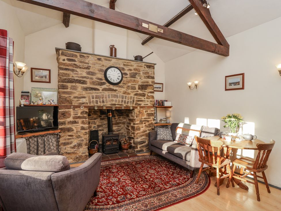 A living room with a fireplace and dining table at Miners Dry in Gulworthy, near Tavistock