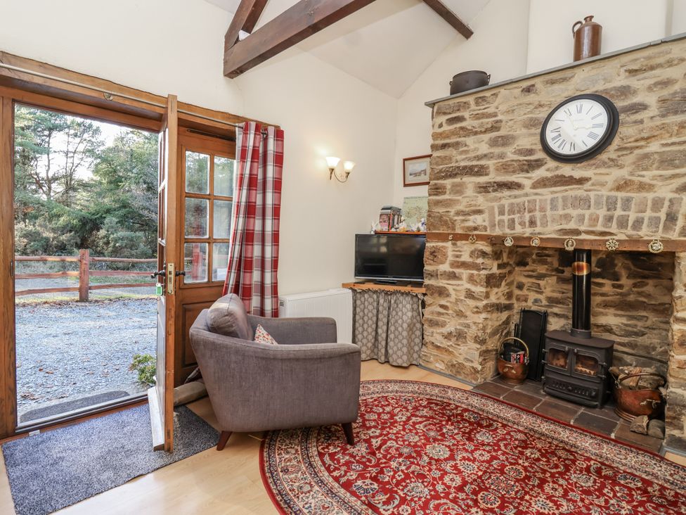 A living room with a fireplace and a chair at Miners Dry in Gulworthy, near Tavistock