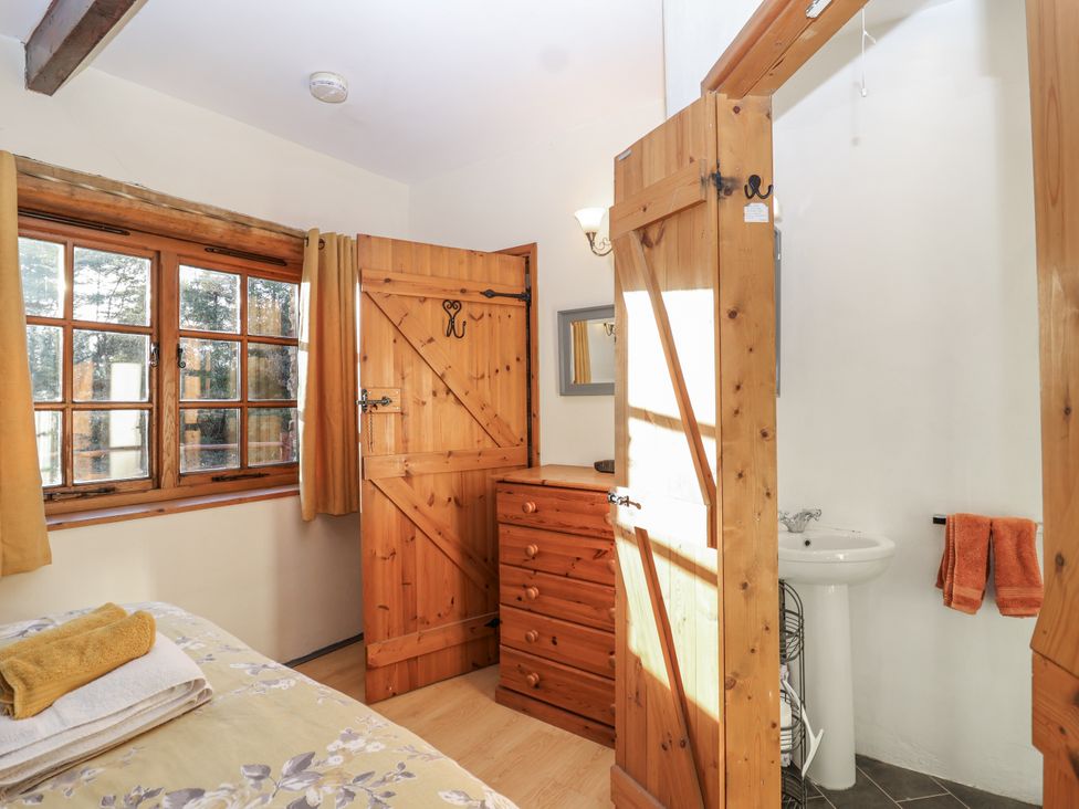 A bedroom with a wooden dresser and bathroom sink at Miners Dry in Gulworthy, near Tavistock