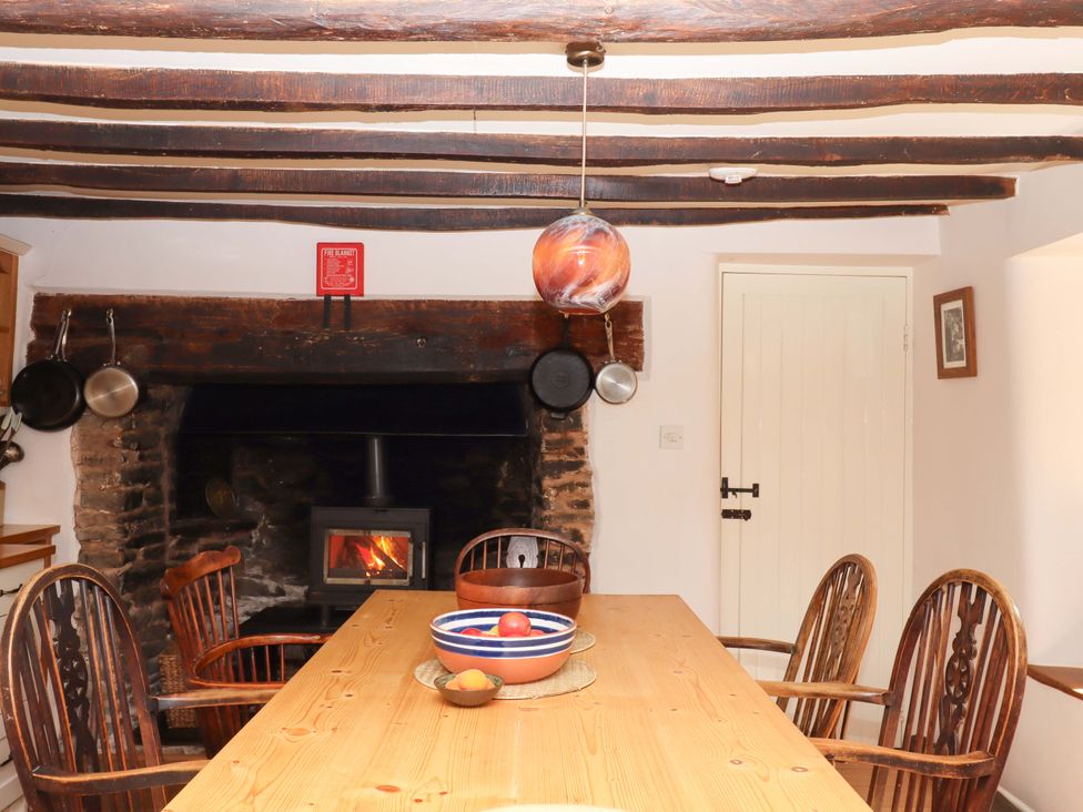 A kitchen with table and chairs near a fireplace at Hope Cottage in Riddlecombe, near Winkleigh