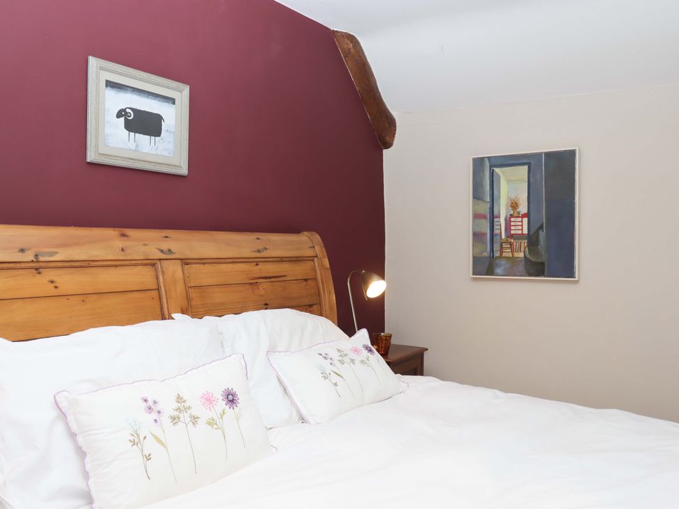 A bedroom with a wooden bed and framed pictures at Hope Cottage Riddlecombe, near Winkleigh