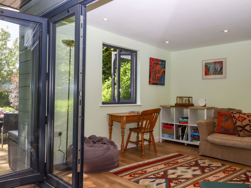A snug with a table, chair, and bookshelf at Hope Cottage in Riddlecombe, near Winkleigh