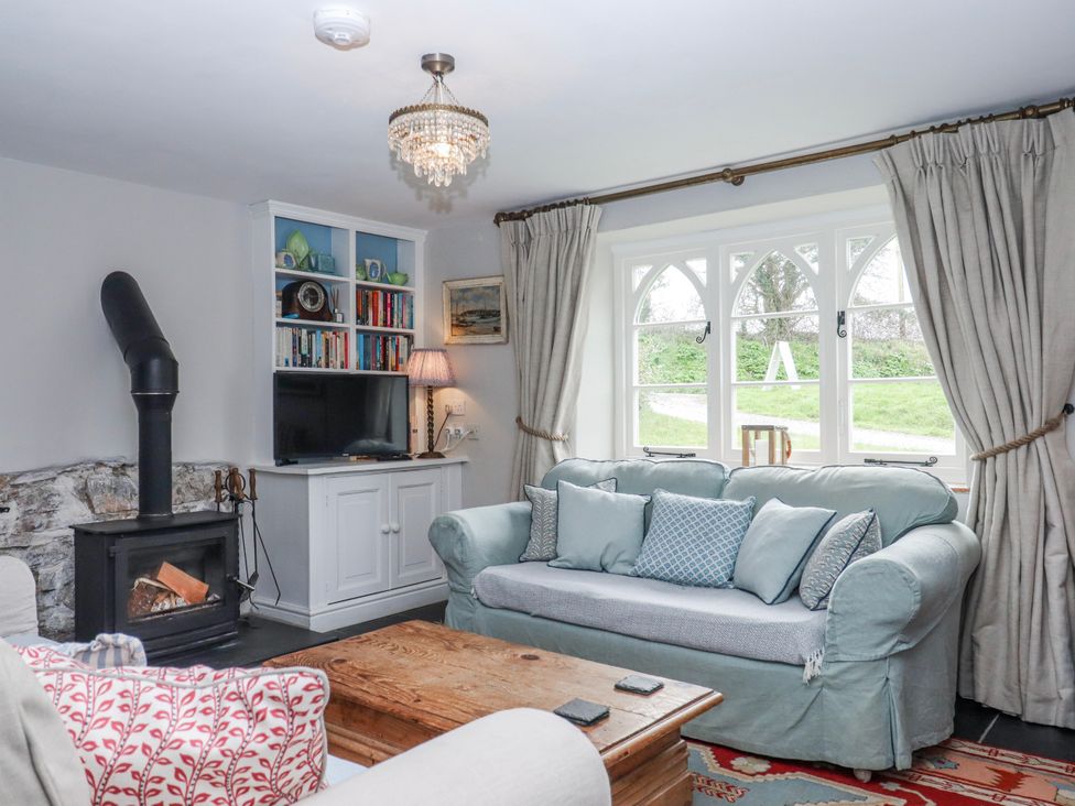 A living room with a brown coffee table and a television at Chapel Cottage in Welcombe