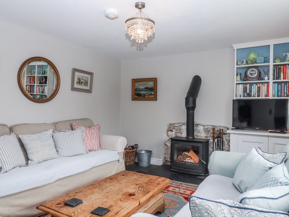 A living room with a fireplace and bookshelf at Chapel Cottage in Welcombe