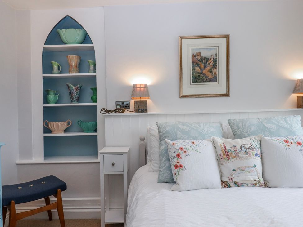 A bedroom with a bed and decorative items on a shelf at Chapel Cottage in Welcombe