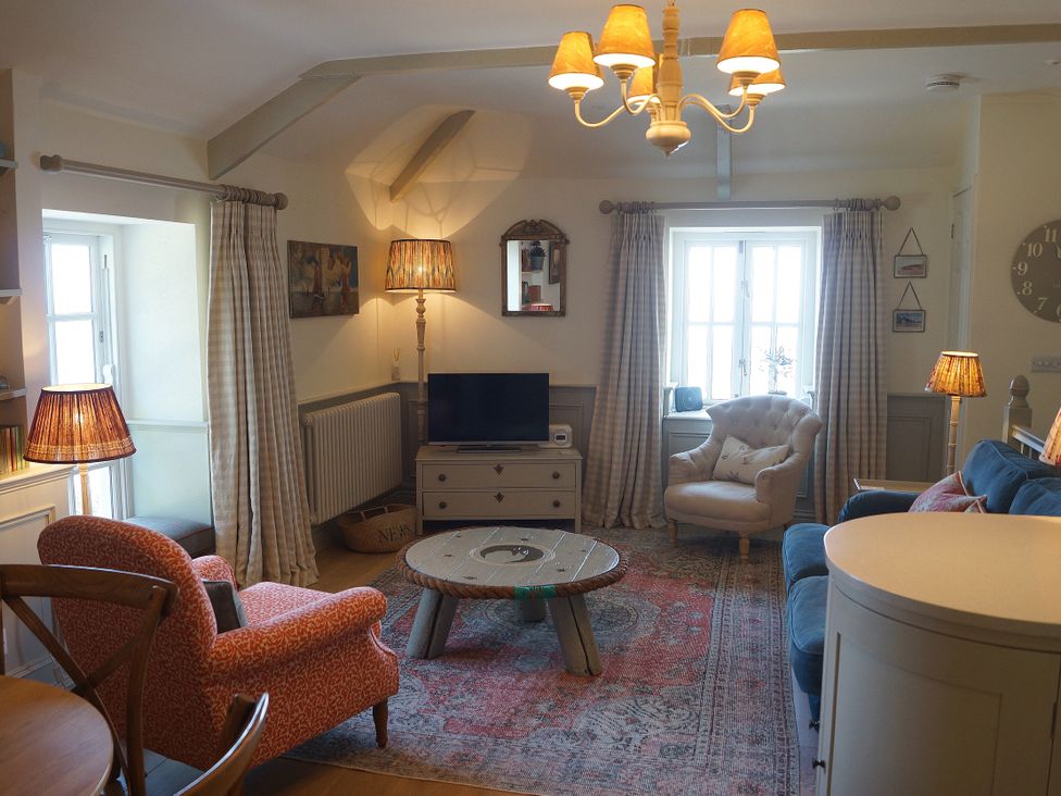 A living room with a sofa, armchair, and coffee table at Coach House Cottage, Strete, near Dartmouth