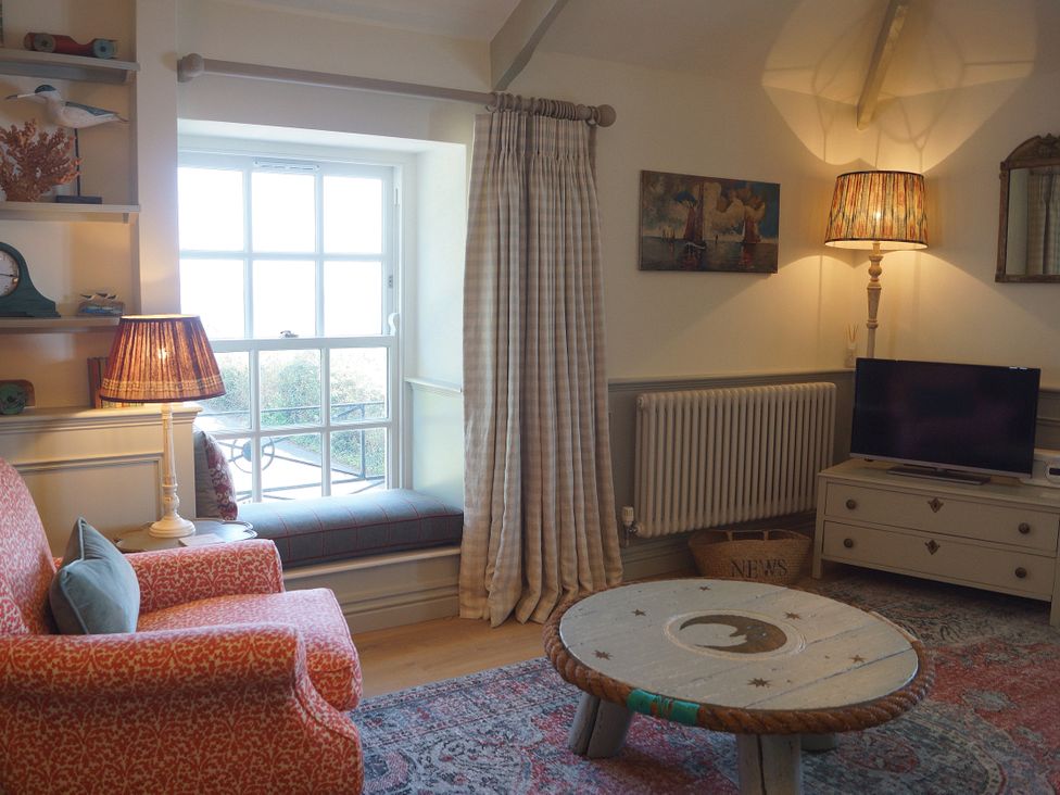 A living room with a window seat and television at Coach House Cottage Strete, near Dartmouth