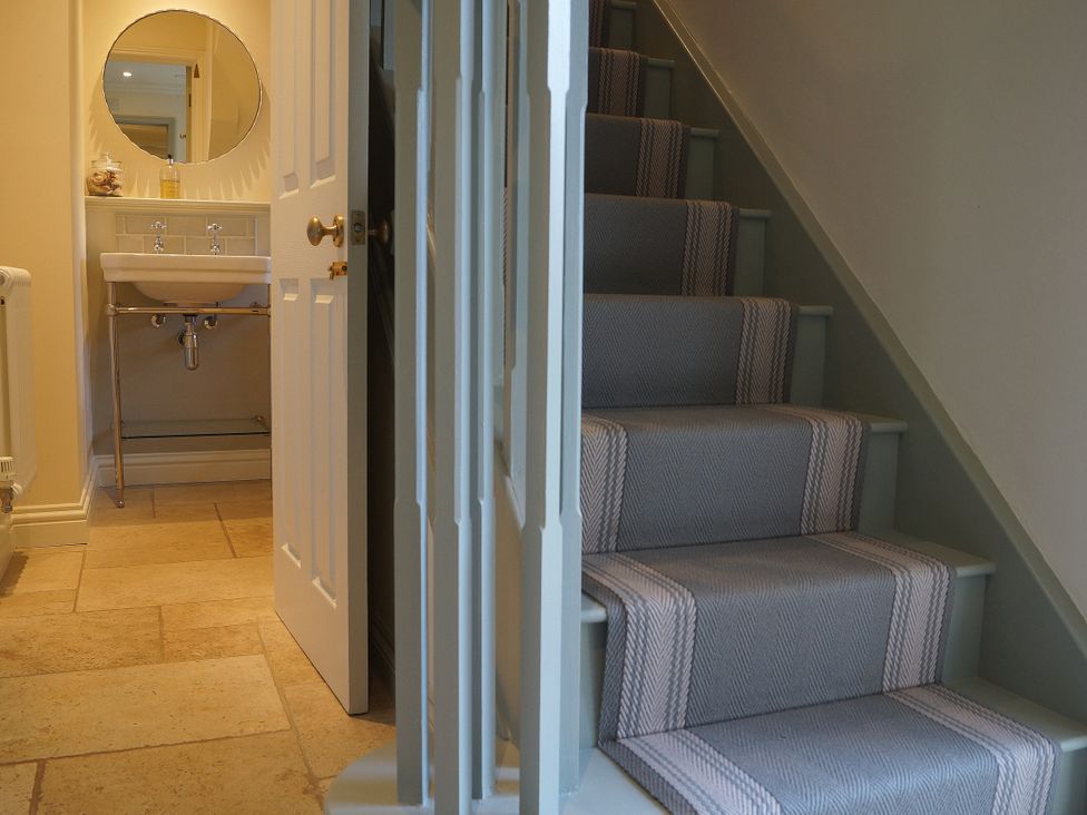 A bathroom with sink and stairs at Coach House Cottage, Strete, near Dartmouth