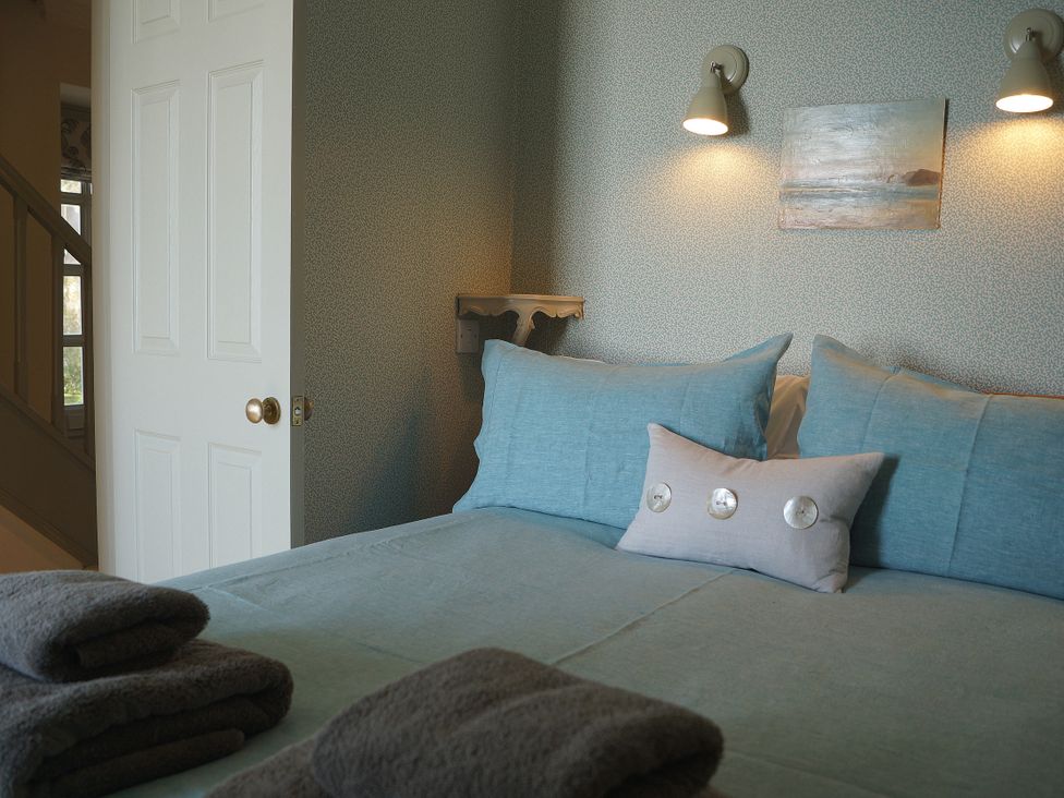 A bedroom with a bed and towels at Coach House Cottage in Strete, near Dartmouth
