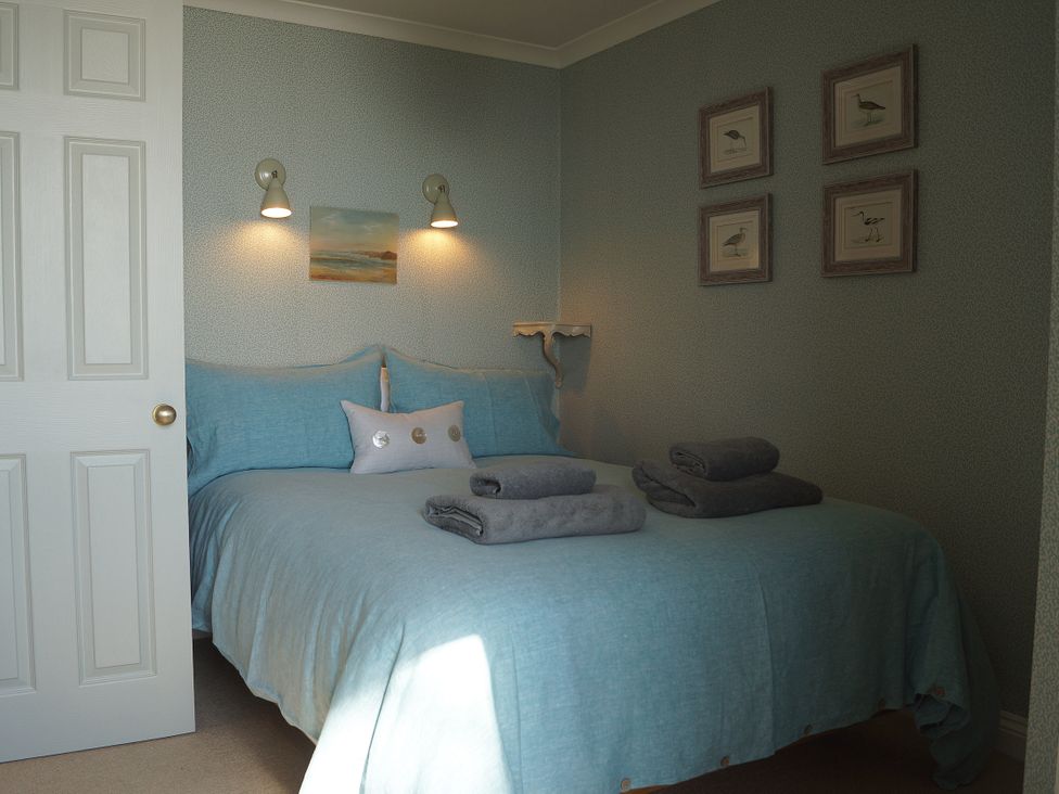 A bedroom with a bed and towels arranged at Coach House Cottage in Strete, near Dartmouth