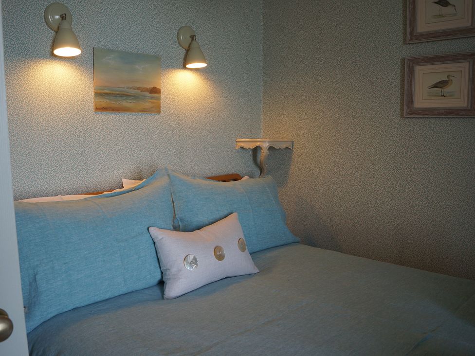 A bedroom with a bed and wall art at Coach House Cottage in Strete, near Dartmouth