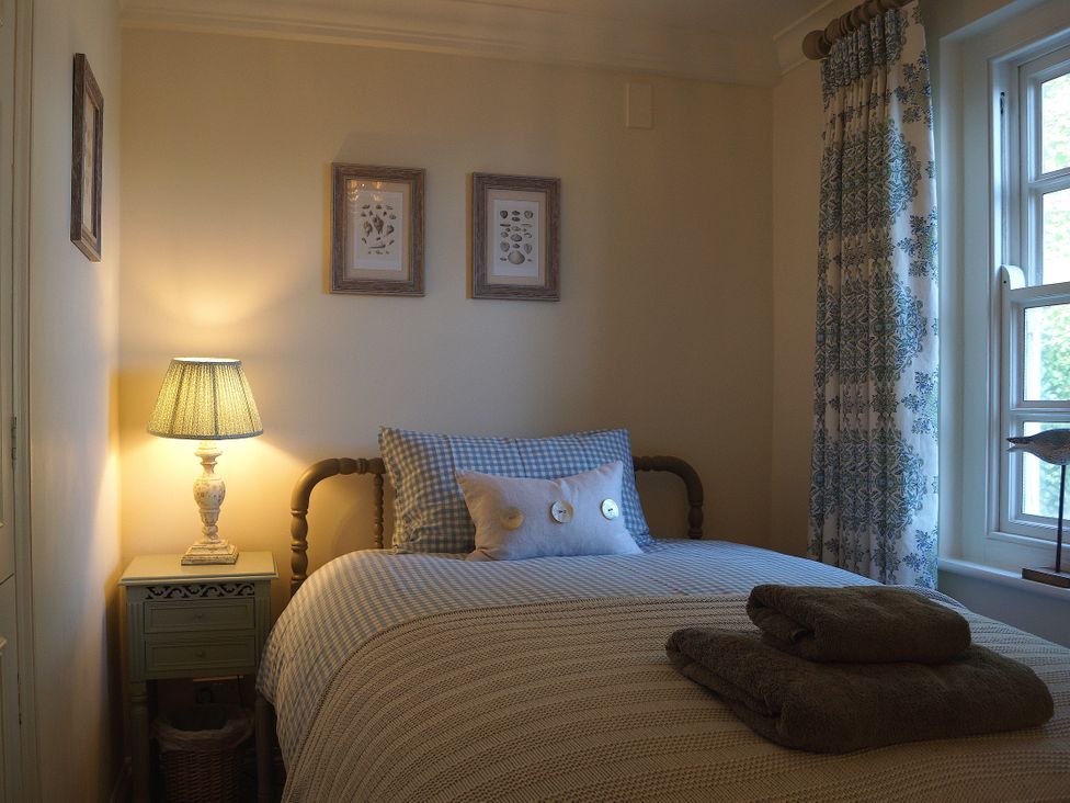 A bedroom with a bed and lamp at Coach House Cottage, Strete, near Dartmouth