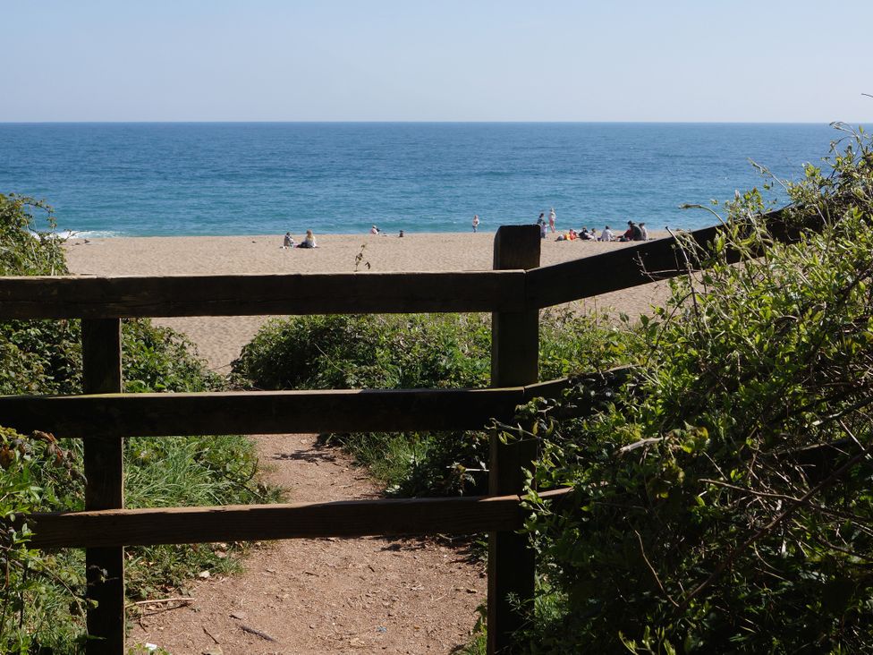 A view of the beach through a wooden gate at Coach House Cottage, Strete, near Dartmouth