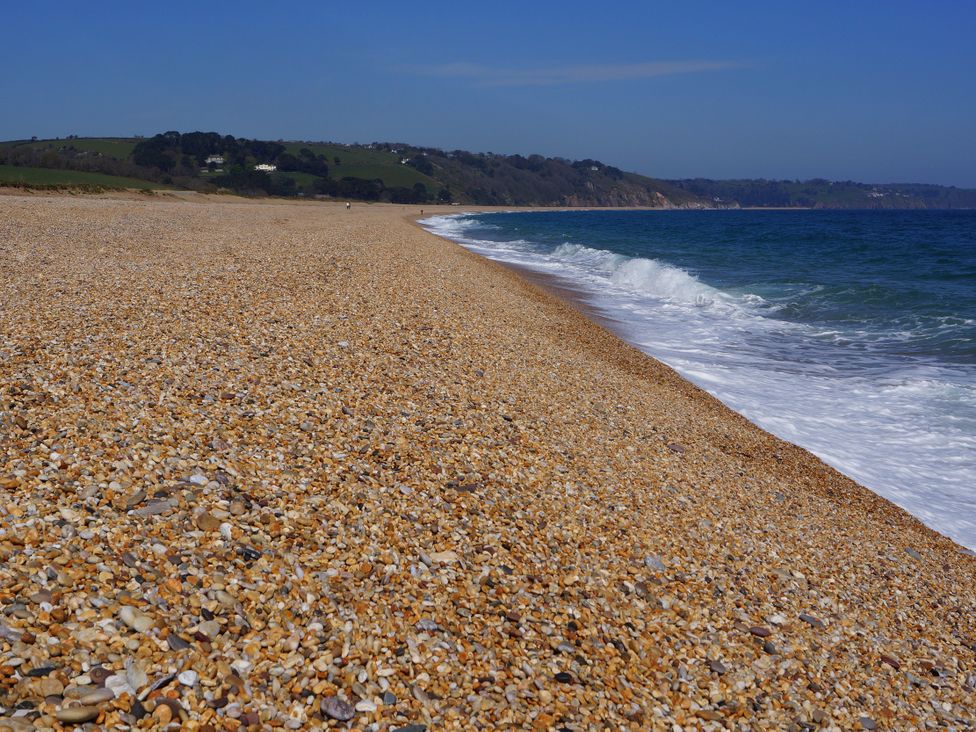 A beach with pebbles and waves at Coach House Cottage in Strete, near Dartmouth