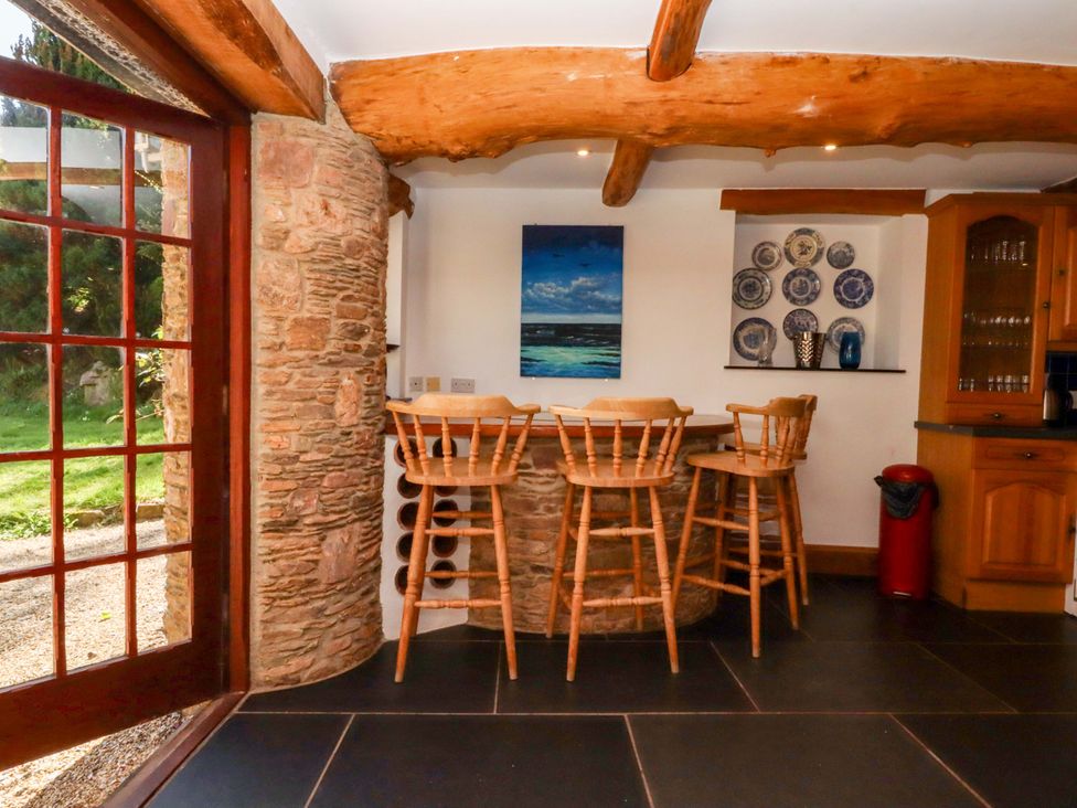 A kitchen with a bar and stools at East Bickleigh Halwell