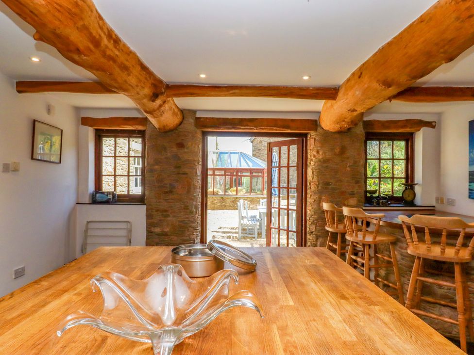 A kitchen with a wooden table and bar stools at East Bickleigh in Halwell