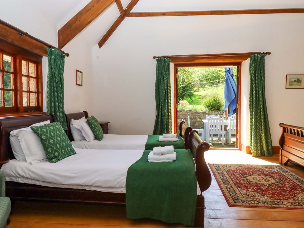 A bedroom with two beds and a door leading to an outdoor seating area at East Bickleigh in Halwell