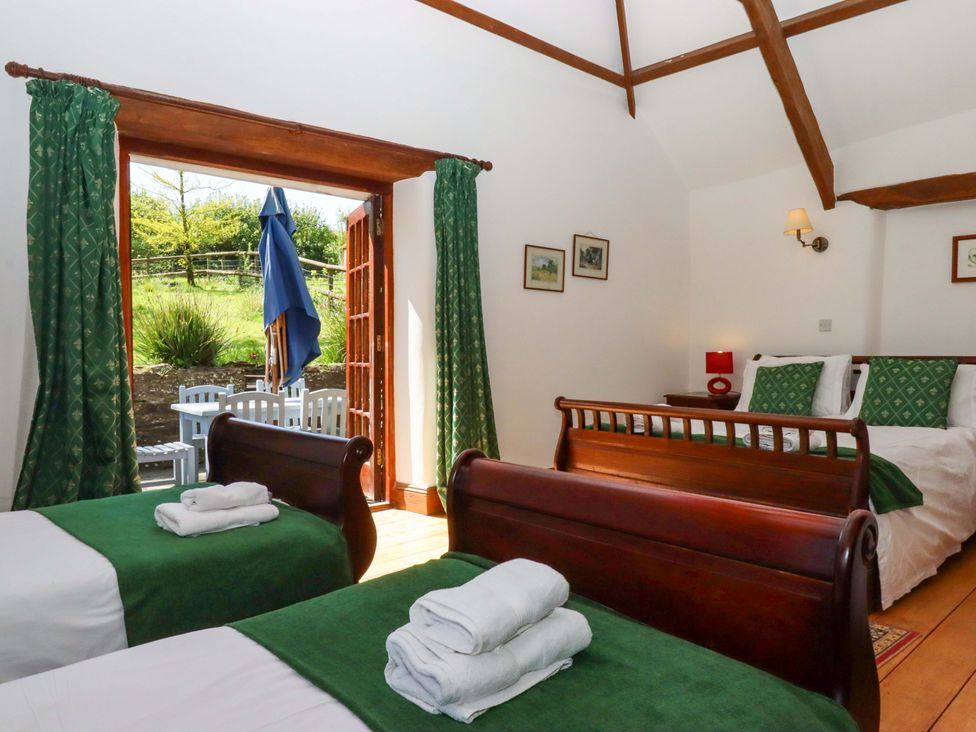 A bedroom with two beds and a view of outdoor seating at East Bickleigh Halwell
