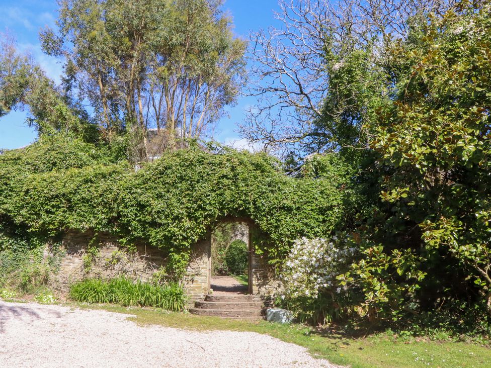 A garden with an archway and pathway at The Music Room near Aveton Gifford