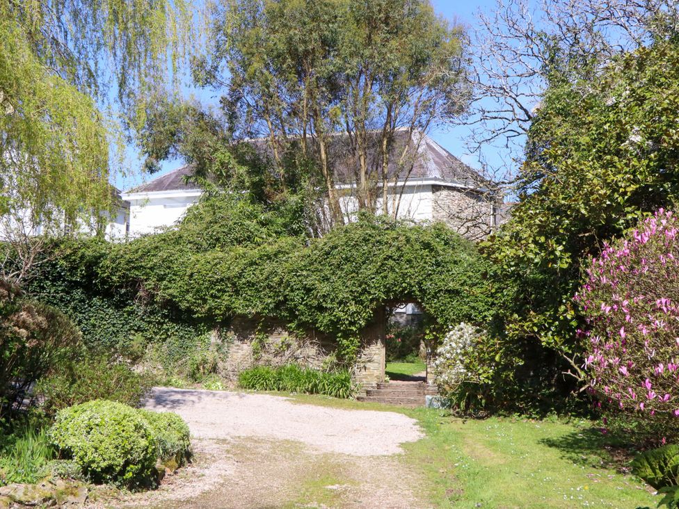 A garden with an archway and flowering bushes at The Music Room near Aveton Gifford