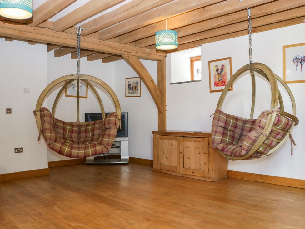 A living room with hanging chairs and a television at The Roundhouse in Halwell