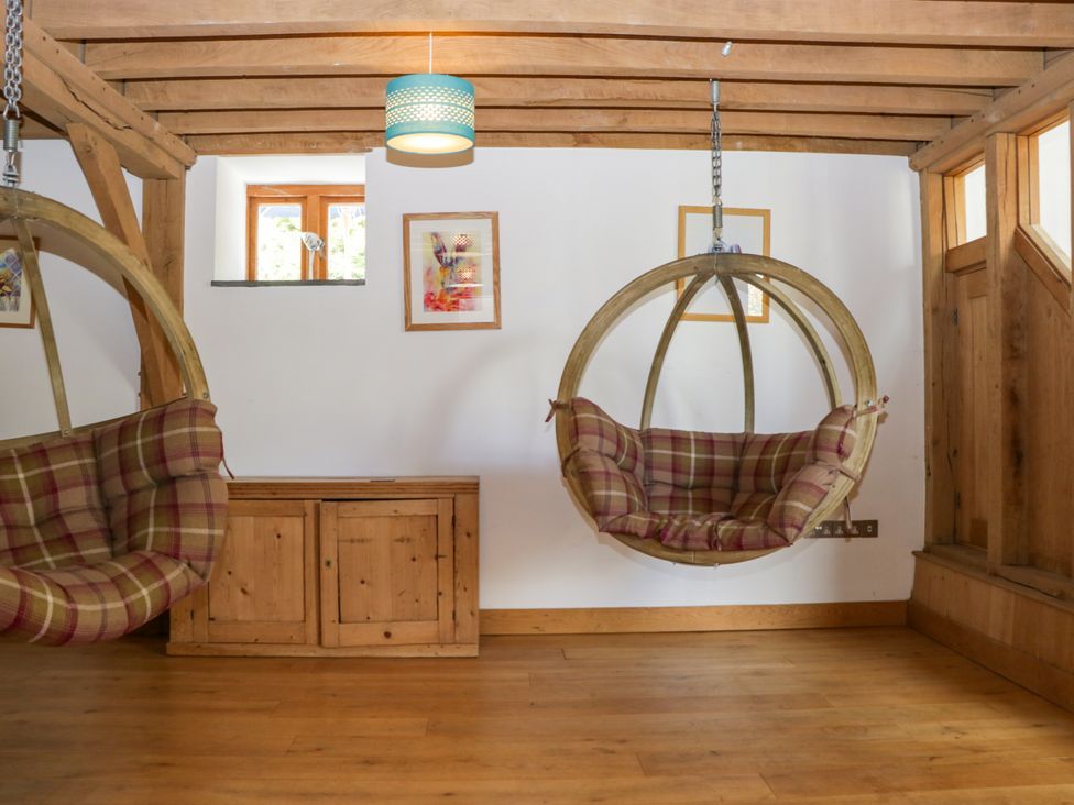 A room with hanging chairs and a wooden cabinet at The Roundhouse in Halwell